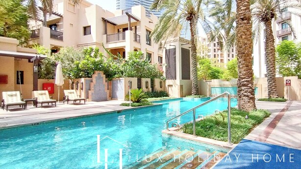 A swimming pool surrounded by palm trees and modern buildings.
