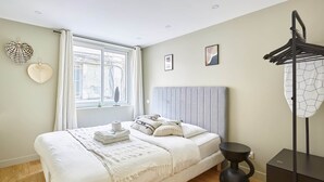 Een keurig opgemaakt slaapkamer met een bed, nachtkastje en hanglamp.