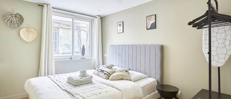 A neatly arranged bedroom with a bed, bedside table, and a hanging light fixture.