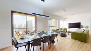 Un soggiorno moderno con zona pranzo, ampie finestre e televisore a schermo piatto.