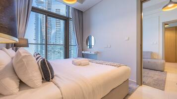 A modern hotel room with a large bed, a vanity with a mirror, and a view of tall buildings through the window.