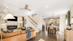 A spacious living room with a fireplace, a sofa, and a dining area with chairs and a table.