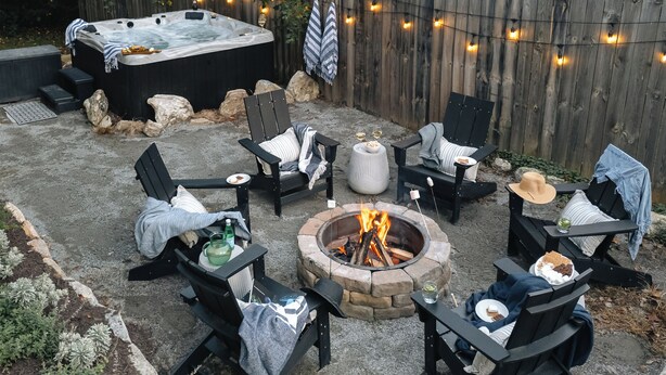 An outdoor patio with a hot tub, fire pit, and seating area.