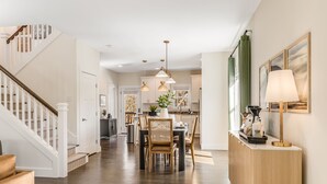 A modern kitchen with pendant lighting, a dining area with a wooden table, and a staircase leading to another level.