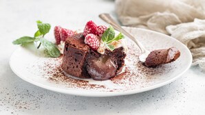 Een chocolade lava cake op een wit bord, met frambozen en muntblaadjes.