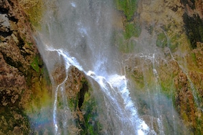 Una cascada fluye sobre terreno rocoso con zonas de vegetación.