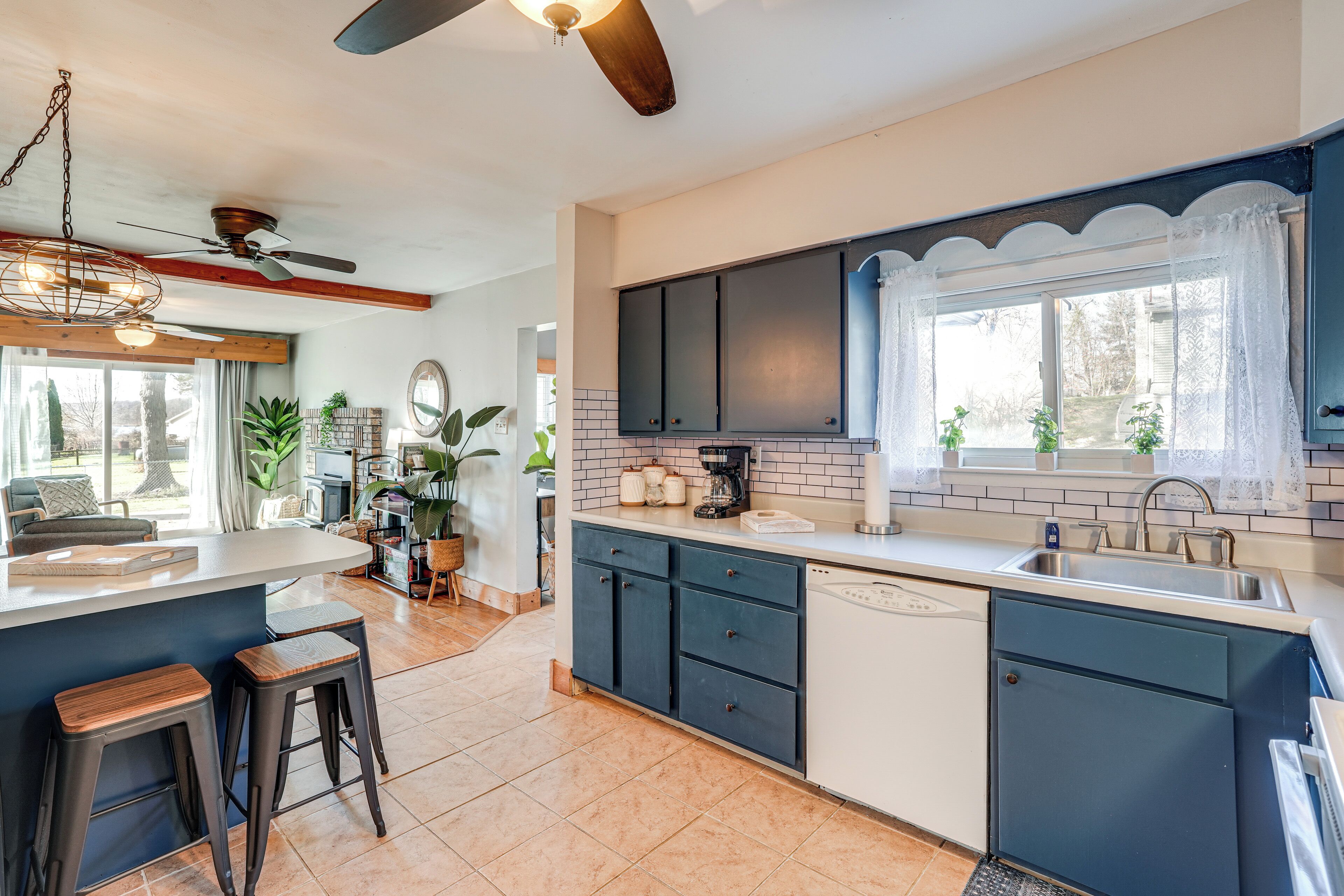A modern kitchen with a central island, dark blue cabinets, and a large window with a view.