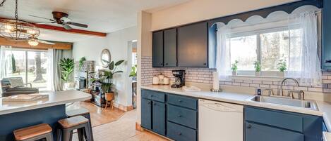 A modern kitchen with a central island, dark blue cabinets, and a large window with a view.