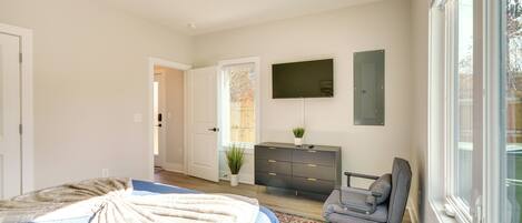 A bedroom with a bed, dresser, chair, and a TV on the wall.