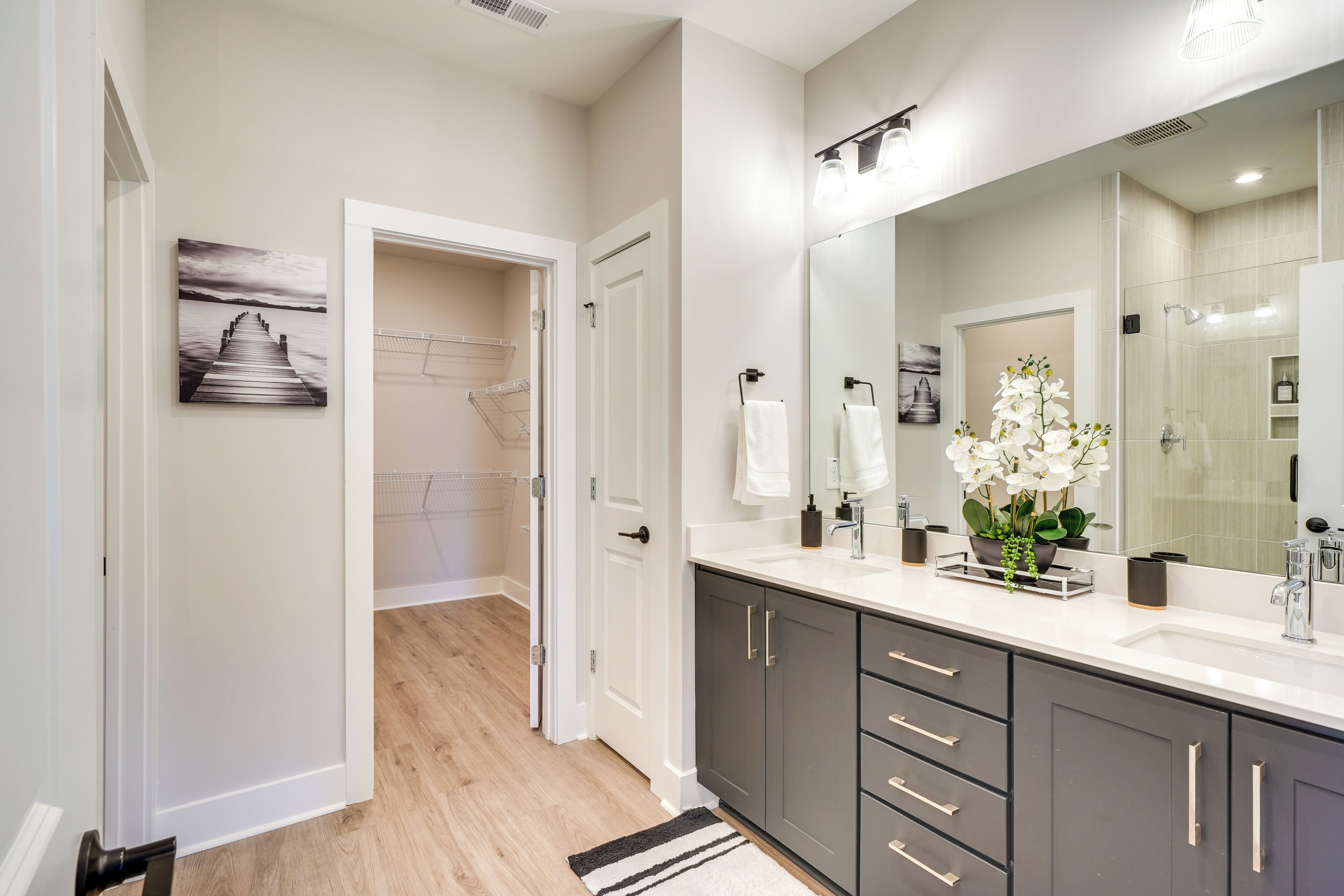 A modern bathroom with a large mirror, a sink, and a shower area.