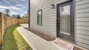 A residential exterior with a grey siding house, a wooden fence, a concrete pathway, and a welcome mat. - 2 Mi to Duke & 3 Mi to Downtown: Durham Townhome (Durham)