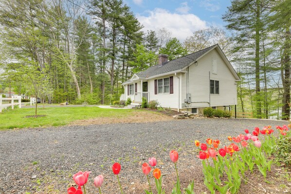 A single-story house with a front porch, surrounded by a gravel driveway and a row of tulips. - < 3 Mi to Uconn: Peaceful Home on Pine Lake (Coventry)