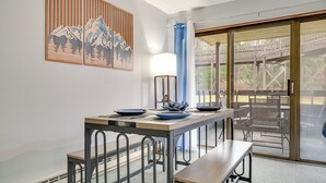 Un comedor con mesa, bancos y vistas a una terraza de madera y asientos exteriores.