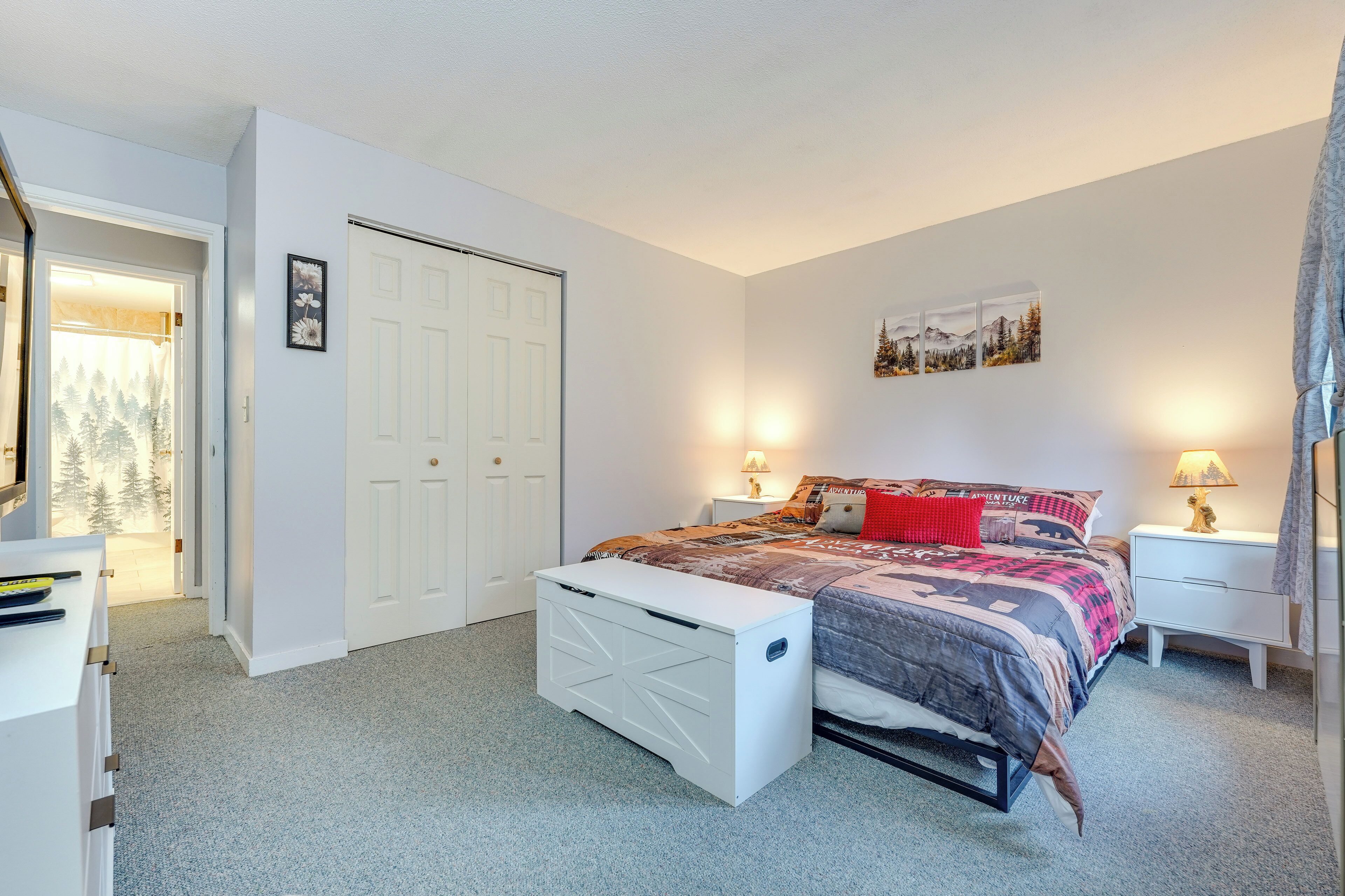 A bedroom with a bed, bedside tables, a wardrobe, and a door leading to a hallway.