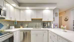 Una cocina moderna con armarios blancos, lavavajillas, microondas y cafetera.