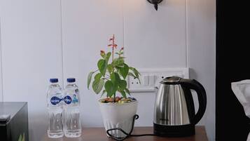 A wooden table with two water bottles, a potted plant, and a coffee maker.