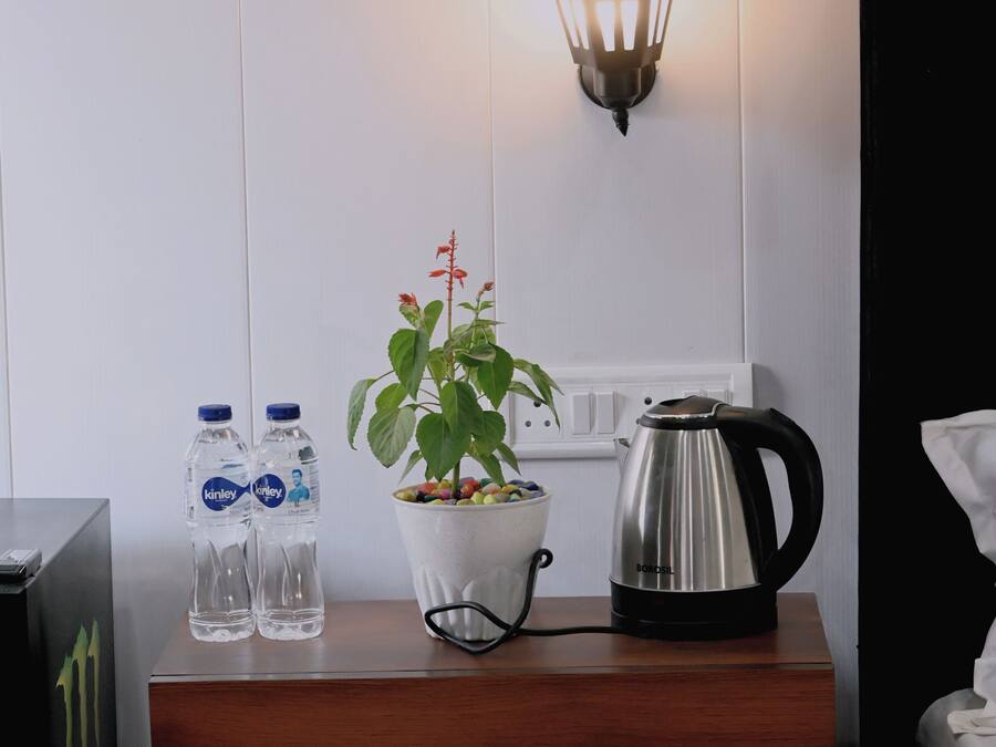 A wooden table with two water bottles, a potted plant, and a coffee maker.