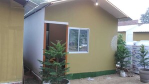 A residential building with a single visible window, a door, and a small porch area with potted plants. - Triveni Sangam Hotels And Resorts (Karchana)