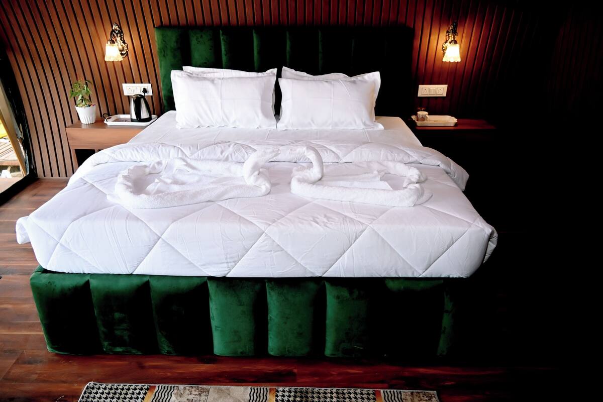 Een keurig opgemaakt bed met witte lakens en twee handdoeken gevouwen in de vorm van een zwaan.
