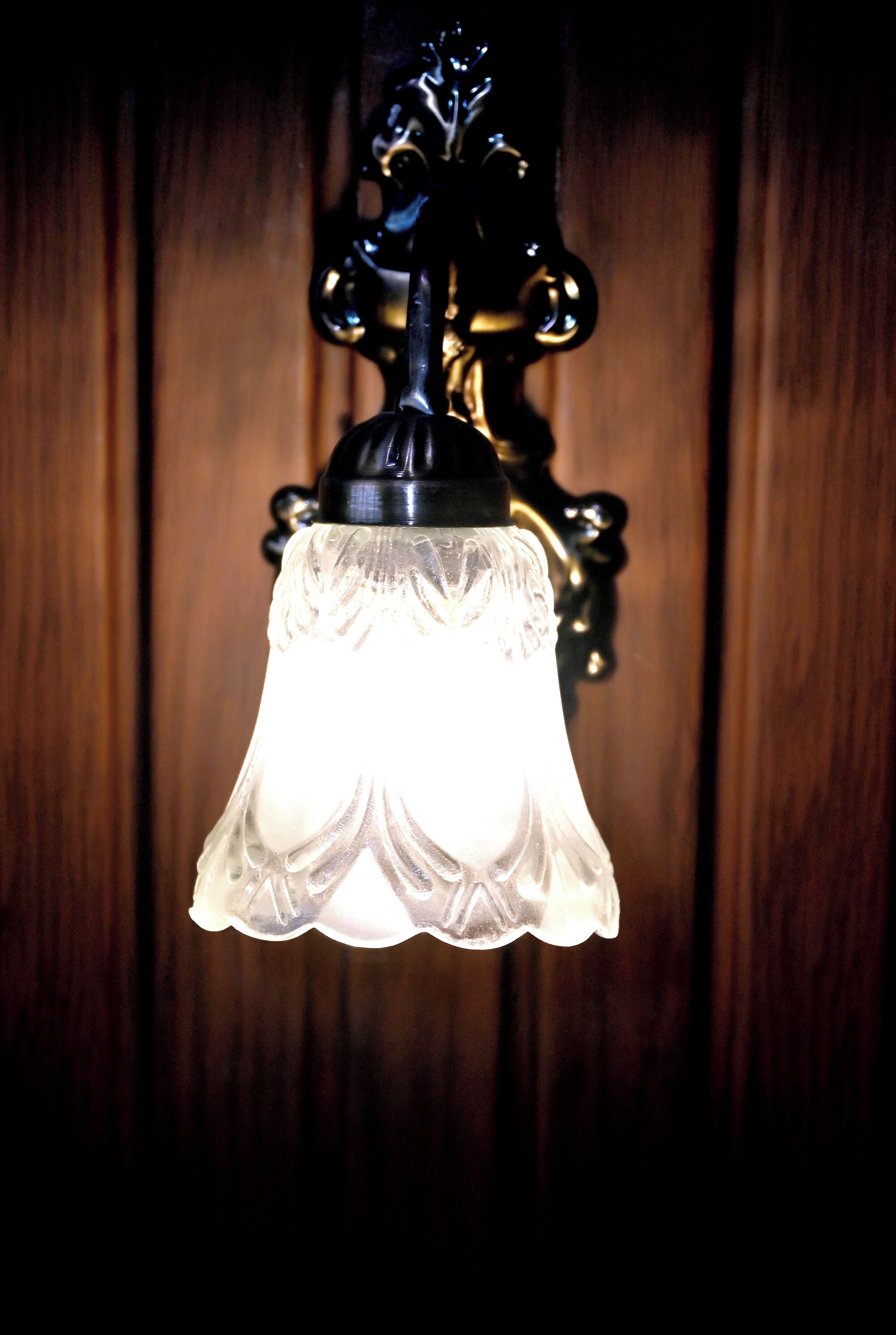 A wall-mounted light fixture with a clear glass shade and a black metal base.