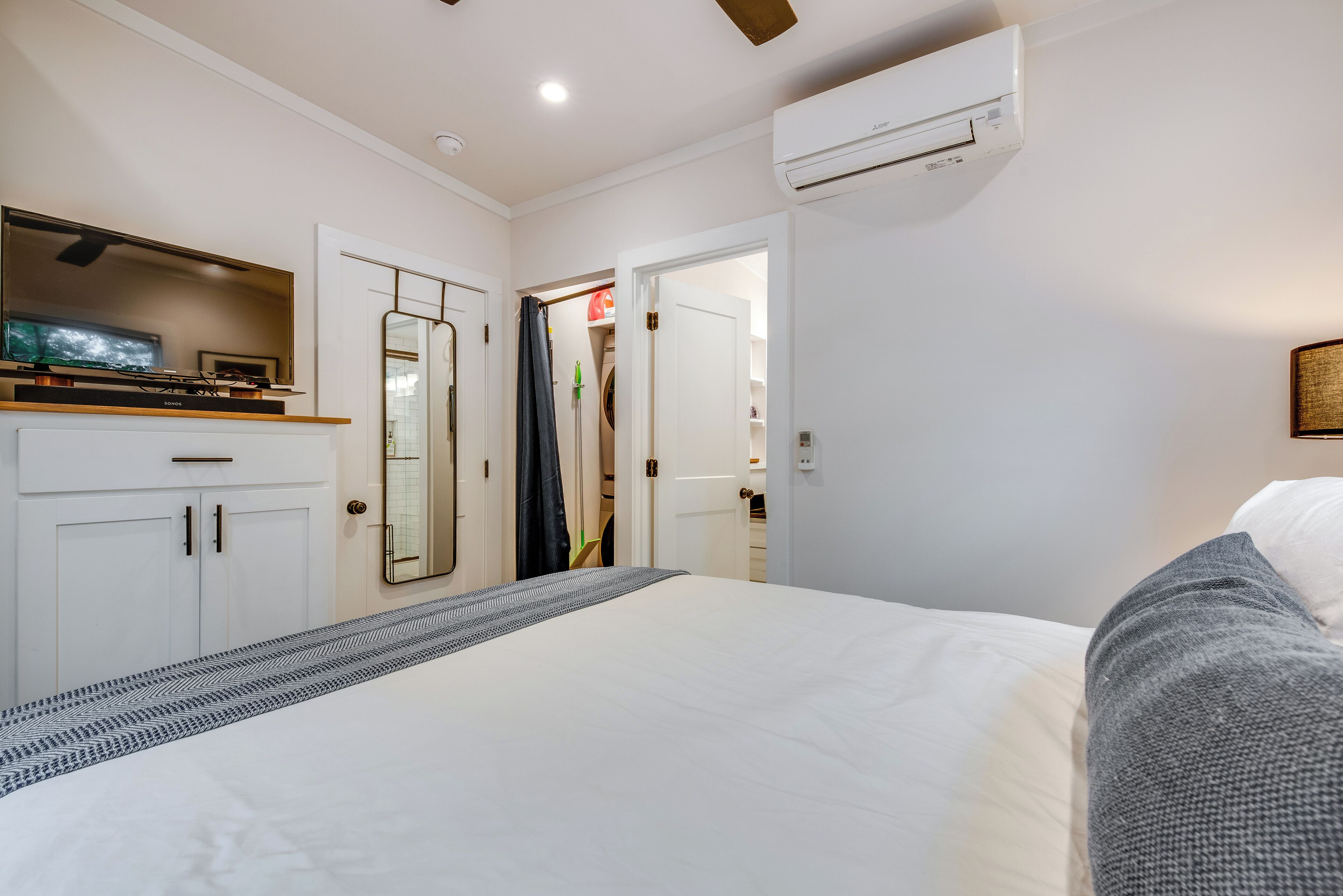 Une chambre à coucher comprenant un lit, une armoire, un miroir et un appareil de climatisation.