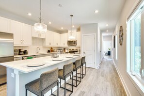 A modern kitchen with white cabinets, a central island with bar stools, a stainless steel refrigerator, and a chandelier. - 2 Mi to Duke University: Townhome in Durham! (Durham)