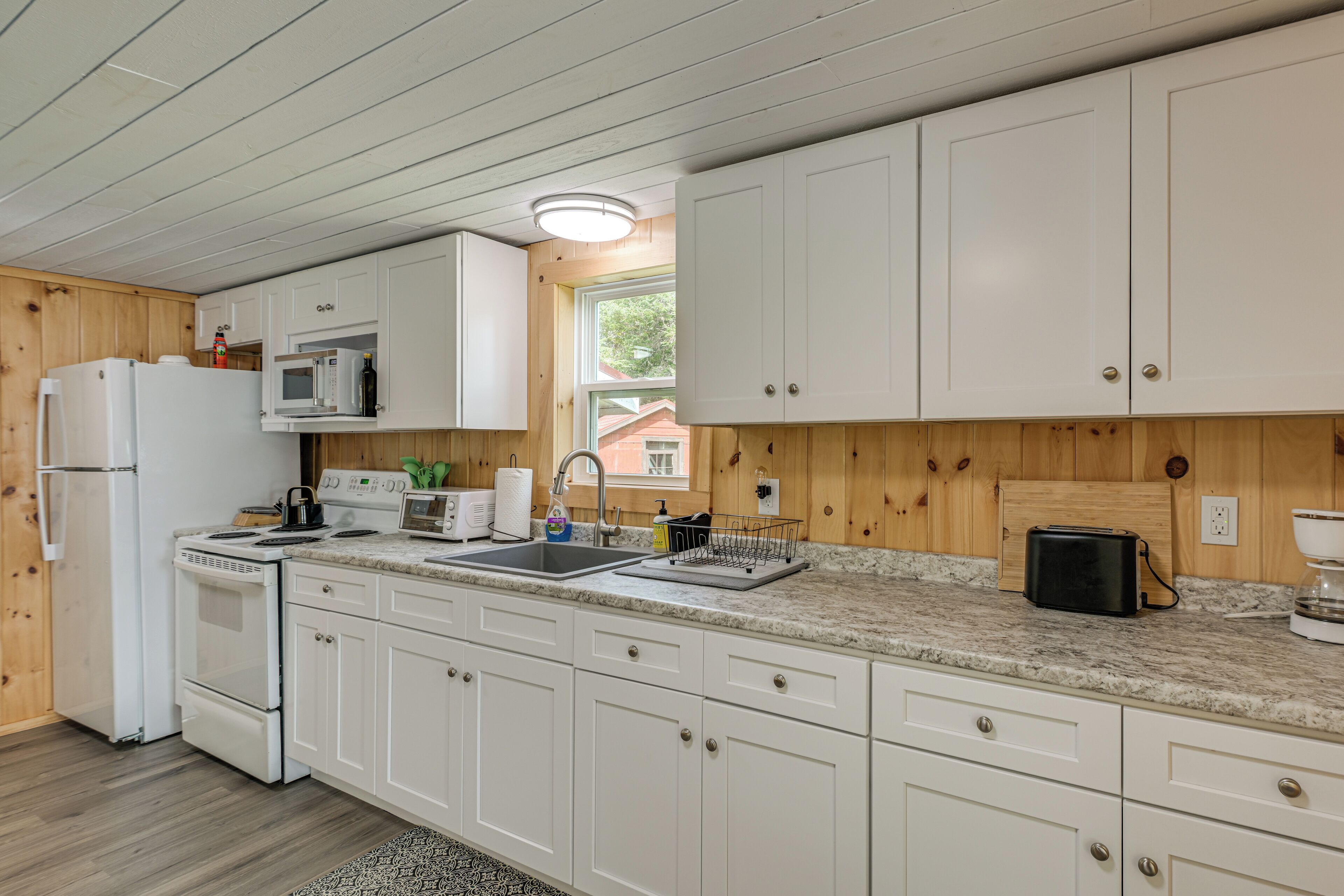 A modern kitchen with white cabinets, a granite countertop, and stainless steel appliances.