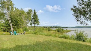 A lakeside view with a grassy area, trees, and a clear sky. - Waterfront Long Lake Retreat: Great for Families! (Sinclair)
