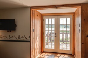 A wooden door with a view of a lake and a wooden deck outside. - Waterfront Long Lake Retreat: Great for Families! (Sinclair)