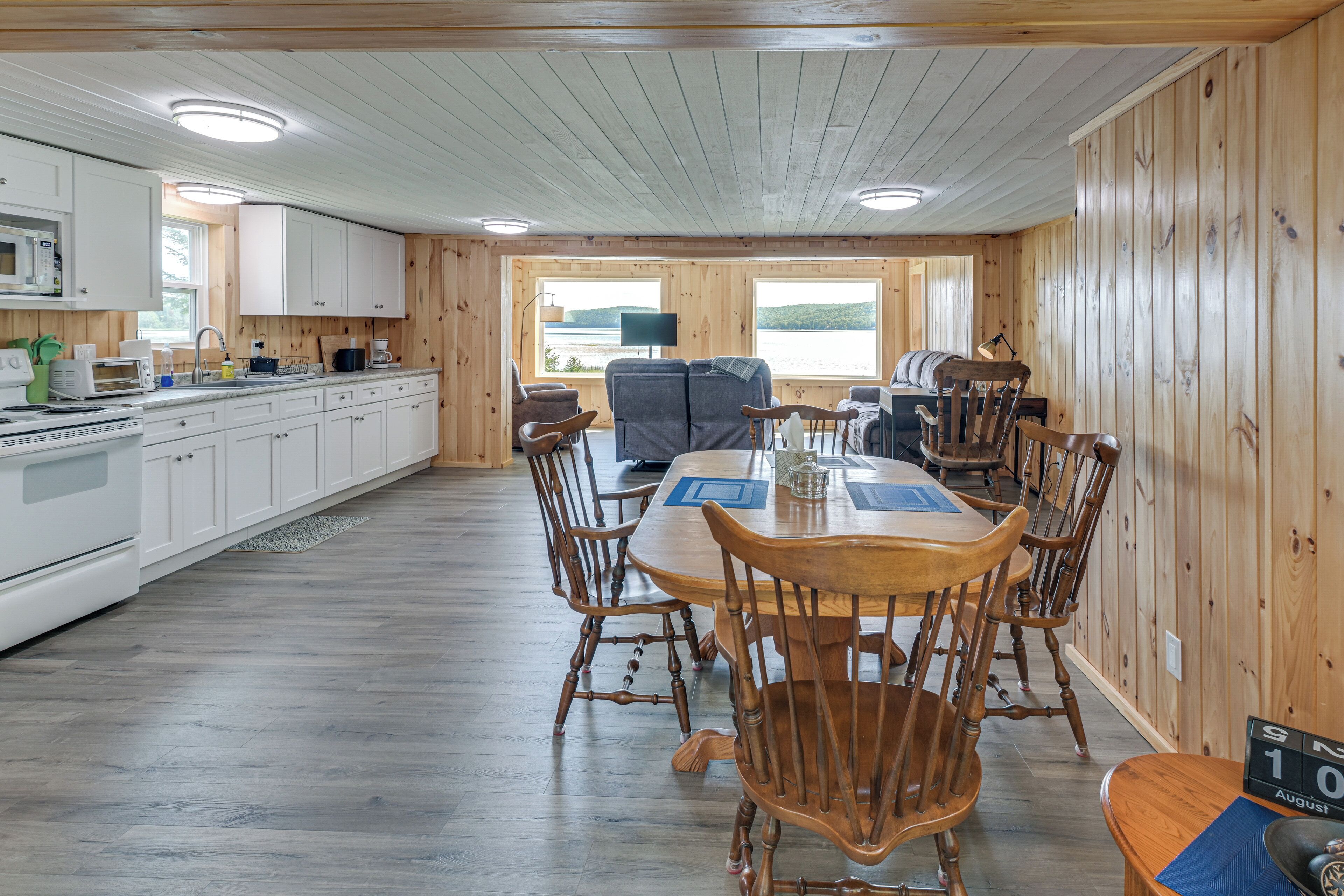 L’intérieur d’une cabane comprenant une cuisine, un coin repas et une vue sur un lac.
