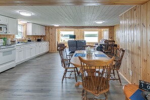 A cabin interior with a kitchen, dining area, and a view of a lake. - Waterfront Long Lake Retreat: Great for Families! (Sinclair)