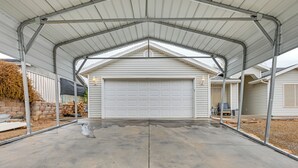 Een garage met een metalen dak en een betonnen oprit.