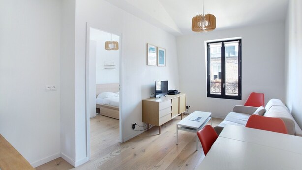 A modern, well-lit room with a bed, a desk, and a dining area. - Apartment Boulogne Facing "les Passages" (Boulogne-Billancourt)