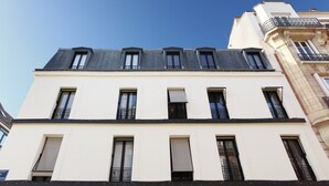 A multi-story building with a white facade, multiple windows, and balconies. - Apartment Boulogne Facing "les Passages" (Boulogne-Billancourt)