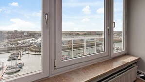 A view from a window overlooking a marina with boats, a bridge, and distant buildings.