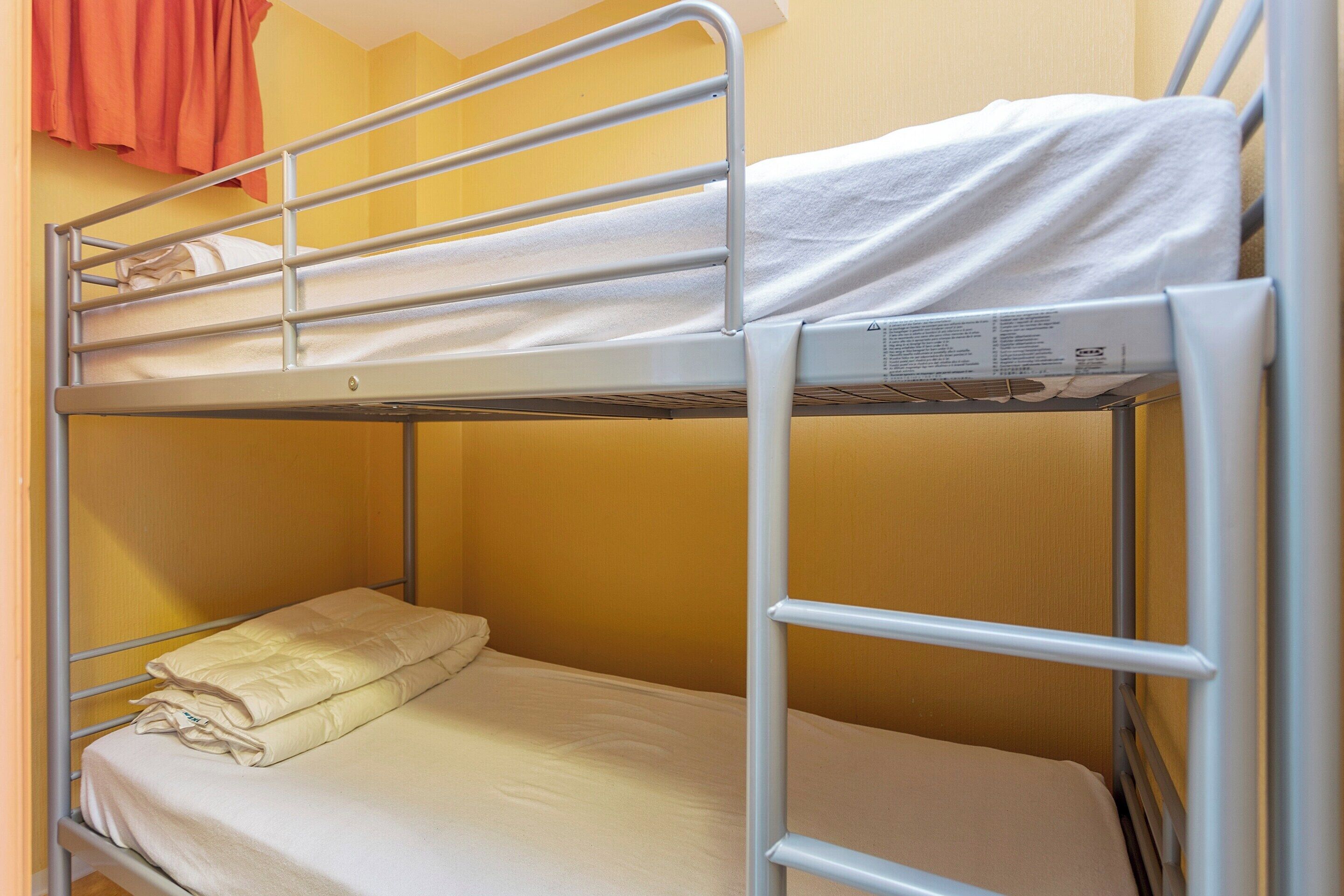 A bunk bed with a metal frame and a lower bunk with a folded blanket.