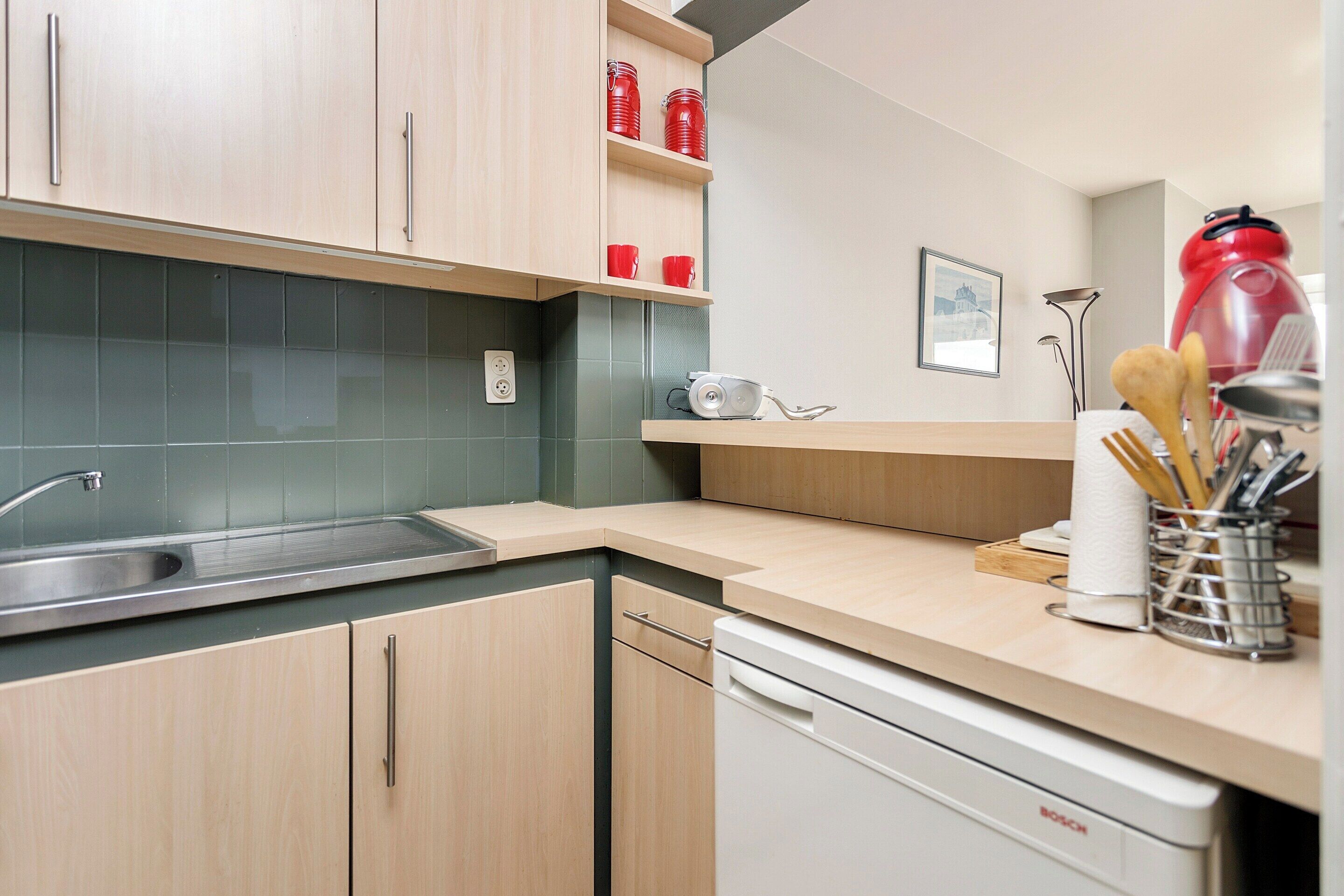 Cocina moderna con armarios de madera, un lavamanos de acero inoxidable y un lavavajillas Bosch.