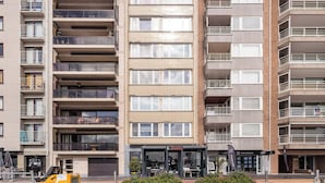 A multi-story residential building with balconies, a restaurant named "IL GUSTO" at the ground level, and a visible sign for "IB BELGIUM".