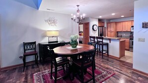 A dining area with a wooden table and chairs, a chandelier, and a red rug. - exquisitely decorated two-bd loft condo, located in The Reserve- Mtn Views! (Sugar Mountain)