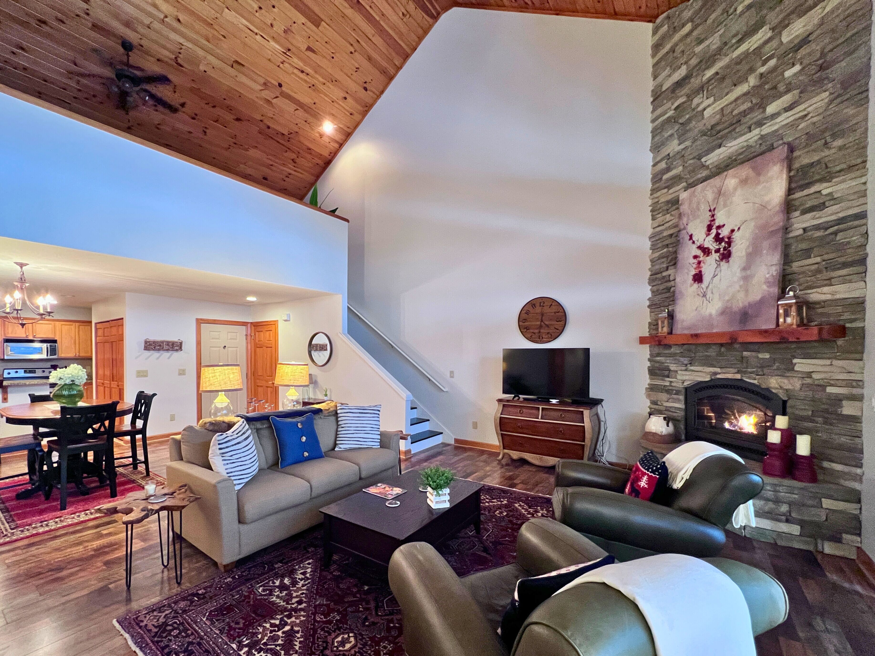 Amplia sala de estar con chimenea, un comedor y una cocina al fondo.