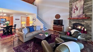 A spacious living room with a fireplace, a dining area, and a kitchen in the background. - exquisitely decorated two-bd loft condo, located in The Reserve- Mtn Views! (Sugar Mountain)