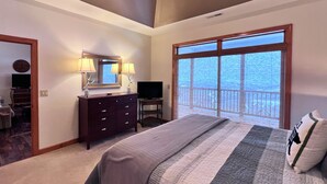 A bedroom with a large bed, a dresser with lamps, a TV, and a balcony with a view. - exquisitely decorated two-bd loft condo, located in The Reserve- Mtn Views! (Sugar Mountain)