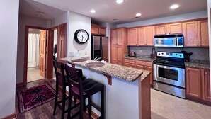 A modern kitchen with wooden cabinets, stainless steel appliances, and a granite countertop. - exquisitely decorated two-bd loft condo, located in The Reserve- Mtn Views! (Sugar Mountain)