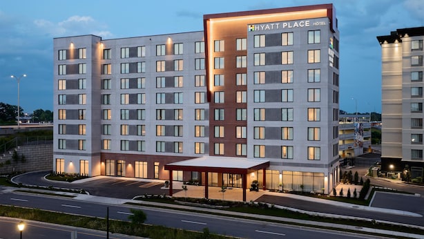 Un hotel moderno de varios pisos, con una entrada destacada y un espacio exterior cubierto.