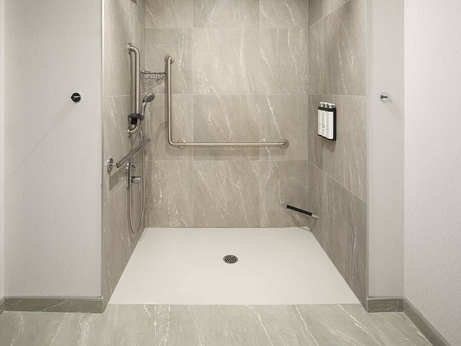 Un baño moderno con ducha a nivel, barras de apoyo y pasamanos.