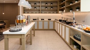 Una cocina moderna con una barra larga, luces colgantes y estantes con plantas en macetas.