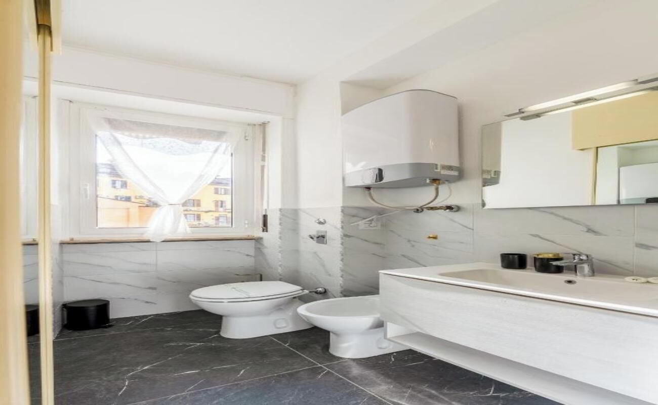 A modern bathroom with a toilet, bidet, and a large mirror above the sink.