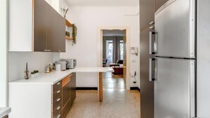 Eine moderne Küche mit Edelstahl-Kühlschrank, weißen Schränken und einer zentralen Kochinsel.