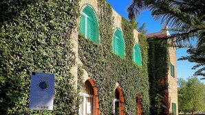 A building with ivy-covered walls and arched windows, a signboard, and a gravel path. - Couleurs Berbères (Lalla Takarkoust)