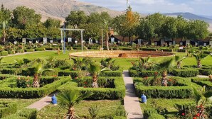 A well-maintained garden with neatly trimmed hedges, palm trees, and a central circular flower bed. - Couleurs Berbères (Lalla Takarkoust)